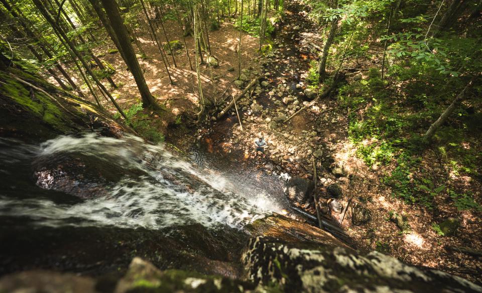 A hiker seen from the top of a waterfall