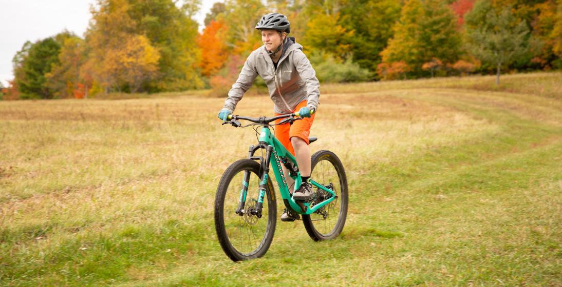 A person biking through a fall field.