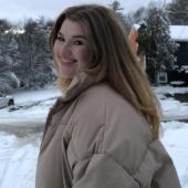 A woman smiles at the camera in a snowy image.