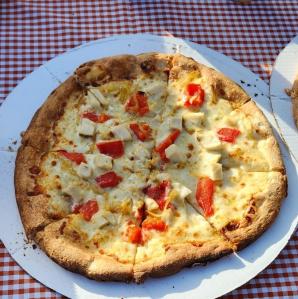 An order of wings and two different style pizzas on a table ordered from bab a dews