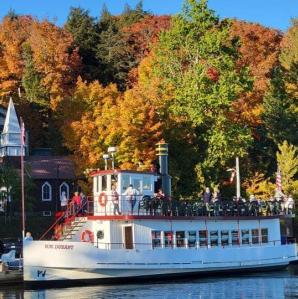 The WW Durant docked on shore with a backdrop of fall colored leaves on the trees behind it