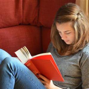 A young woman sitting on a couch reading a book