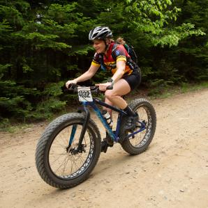 Cyclists in colorful jerseys and helmets gather at the starting line of the Black Fly Challenge in the Adirondacks.