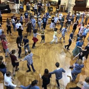 a gymnasium of people contra dancing