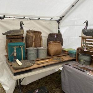 A table of old pack baskets and duck decoys