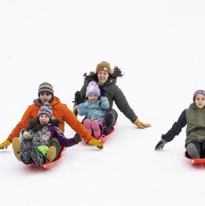 A family sledding down a hill