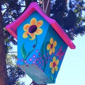 hand painted bird house hanging in tree.