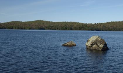 A couple large rocks sticking out of a pond.