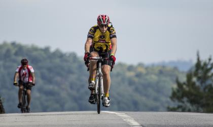 A cyclist cresting a hill on the road.