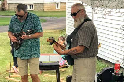 A photo of tim and norm playing their stringed instruments outside
