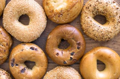 A photo of a variety of bagels laid out on a wooden board