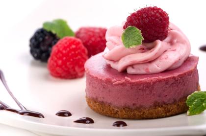 a raspberry cheese cake with pink whipped topping and a raspberry garnish