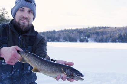A man holding a fish he caught while ice fishing