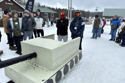 Two sledders standing next to their cardboard sled tank