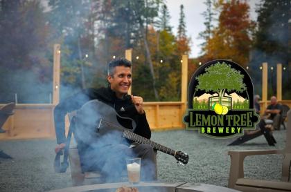 A phot of Kevin Alexander siiting in a chair out side of the Lemon Tree Brewery with his guitar