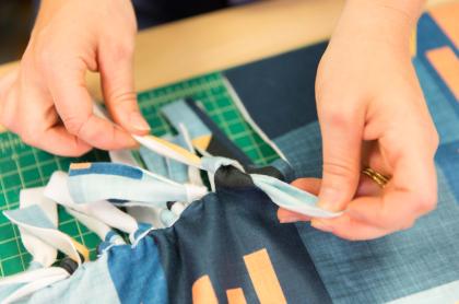 a person tying the ends to make a no-sew blanket