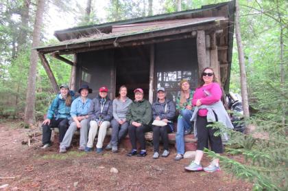 Several ladies sitting in a lean to for a group phot at great camp sagamore