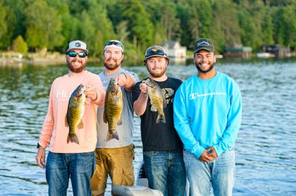 four men standing in front of a lake