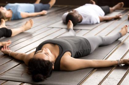 Several people laying on their backs on yoga mats looking relaxed