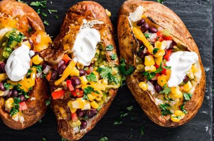 A photo of three baked potatoes loaded with a variety of toppings