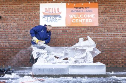 Man carving a snowmobile out of ice