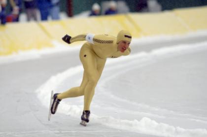 A man is a speedskating uniform racing around an ice track