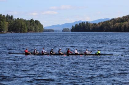 A crew of men on a rowing team rowing their boat on a lake