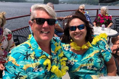 A man and his wife wearing matching hawaiian shirts and yellow leis on board the Durant