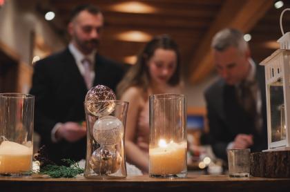 People getting food in the background with the focus of the holiday decorations of candles and glittery ornaments in the foreground of the photo