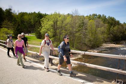 A group of people walking together across a footbridge bridge