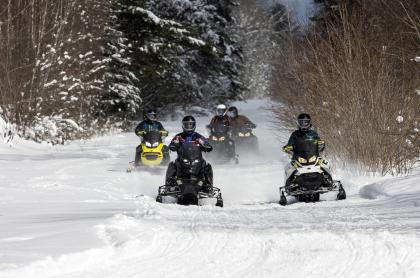 Four snomobiles riding on a trail