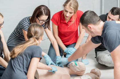 A CPR instructor teaching skills to a class as they sit around a CPR dummy