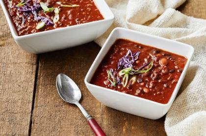 Two bowls of chili with a spoon.
