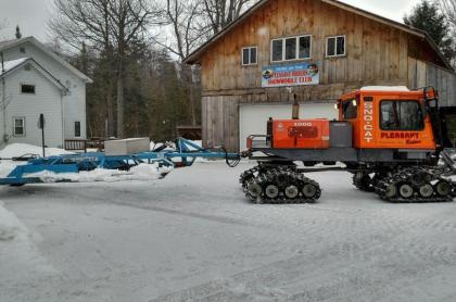 the outside of the pleasant riders garage with a snowmobile trail groomer