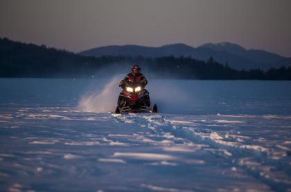 A person on a snowmobile travels across a snowy field