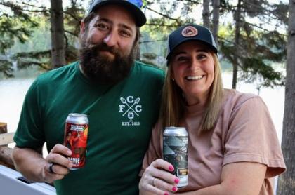 A couple posing for a photo holding a can of craft beer