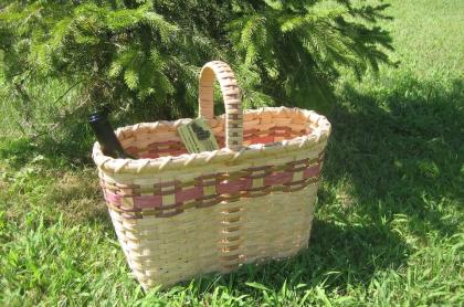 a hand-made wine basket with 2 bottles of wine in it sitting on green grass