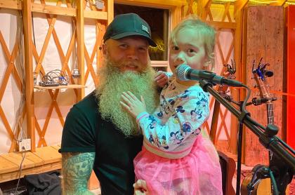 A picture of Josh holding his little girl up to the microphone