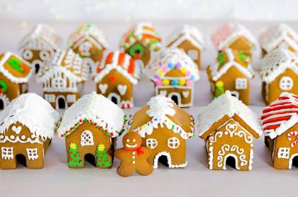 A gingerbread man cookie standing in front of three rows of mini gingerbread houses all nicely decorated