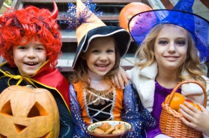 Three kids dressed up for halloween posing for a photo