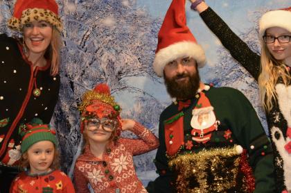 A family all wearing ugly Christmas sweaters and posing for a photo