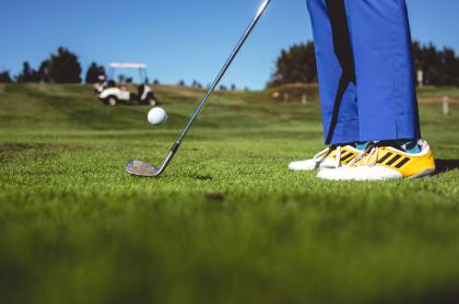 picture from the golf green of person in yellow and white golf shoes and bright blue pants