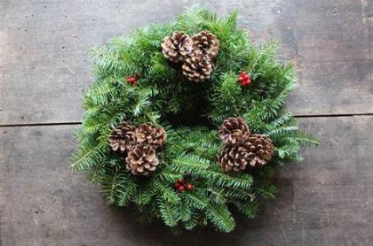 A wreath made from Balsam fir branches and decorated with pinecones and red berries