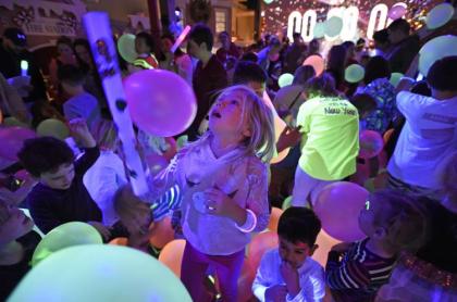 kids in a room with a blck light glowing and balloons falling