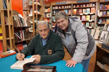 A photo of Phil Bayly and a fan as he signs her book