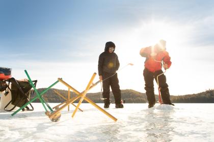 Two ice fishermen setting up gear on a frozen lake. 