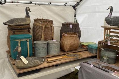 A table of old pack baskets and duck decoys