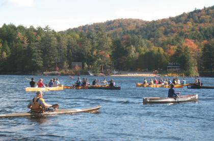 several long boats off the shore of long lake beach paddling in the long boat regatta