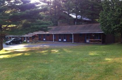 The large lawn and exterior of the brown building and white trim of the Blueberry Hill Motel
