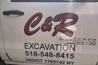 A White work truck door with red C & R Excavation on the side.